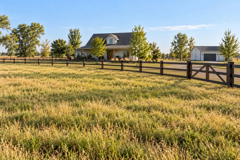 Erie pasture and farmhouse enclosed by post-and-rail fencing.